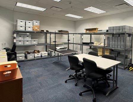 A room with open metal shelves storing archival boxes and supplies.